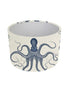 A cylindrical lampshade featuring a blue octopus illustration printed on an off-white linen-textured background, shown against a plain white studio backdrop.