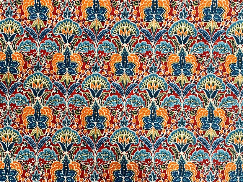 A close-up of a repeating ornate floral pattern with blue, teal, orange, red, and cream elements filling the frame.